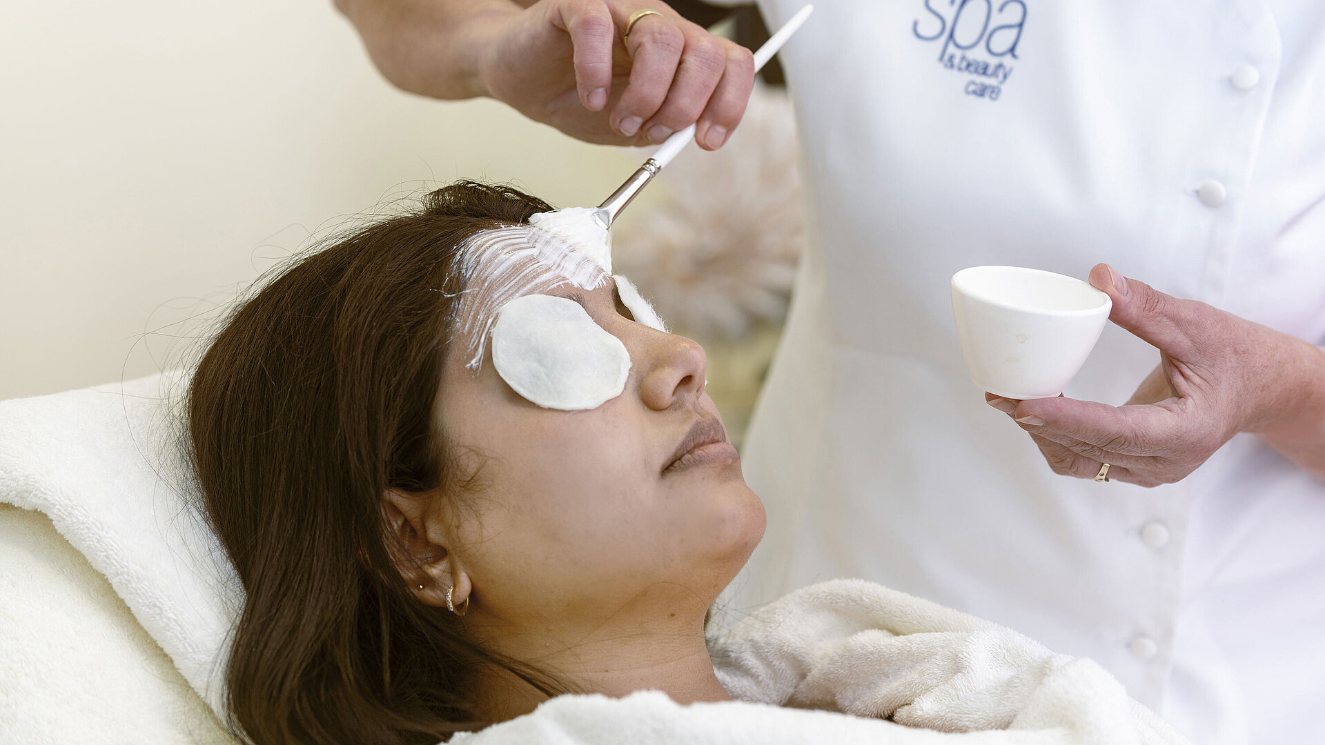 Facial treatment at the Maritim Hotel Spa: A woman receives a face mask and relaxing care with cotton pads.