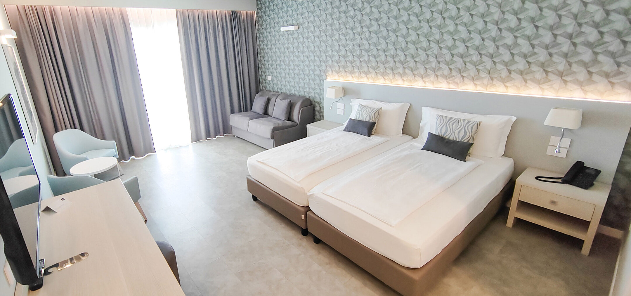 Chambre spacieuse au Maritim Resort Calabria avec lits jumeaux, canapé et bureau clair
