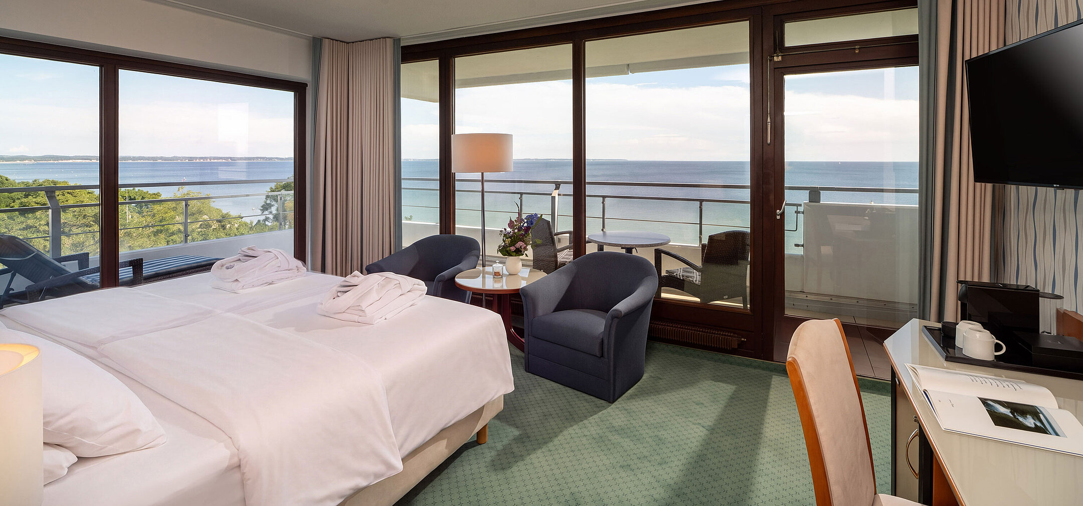 Luminosa camera doppia con ampio letto, area salotto e finestre a tutta altezza con vista sul Mar Baltico