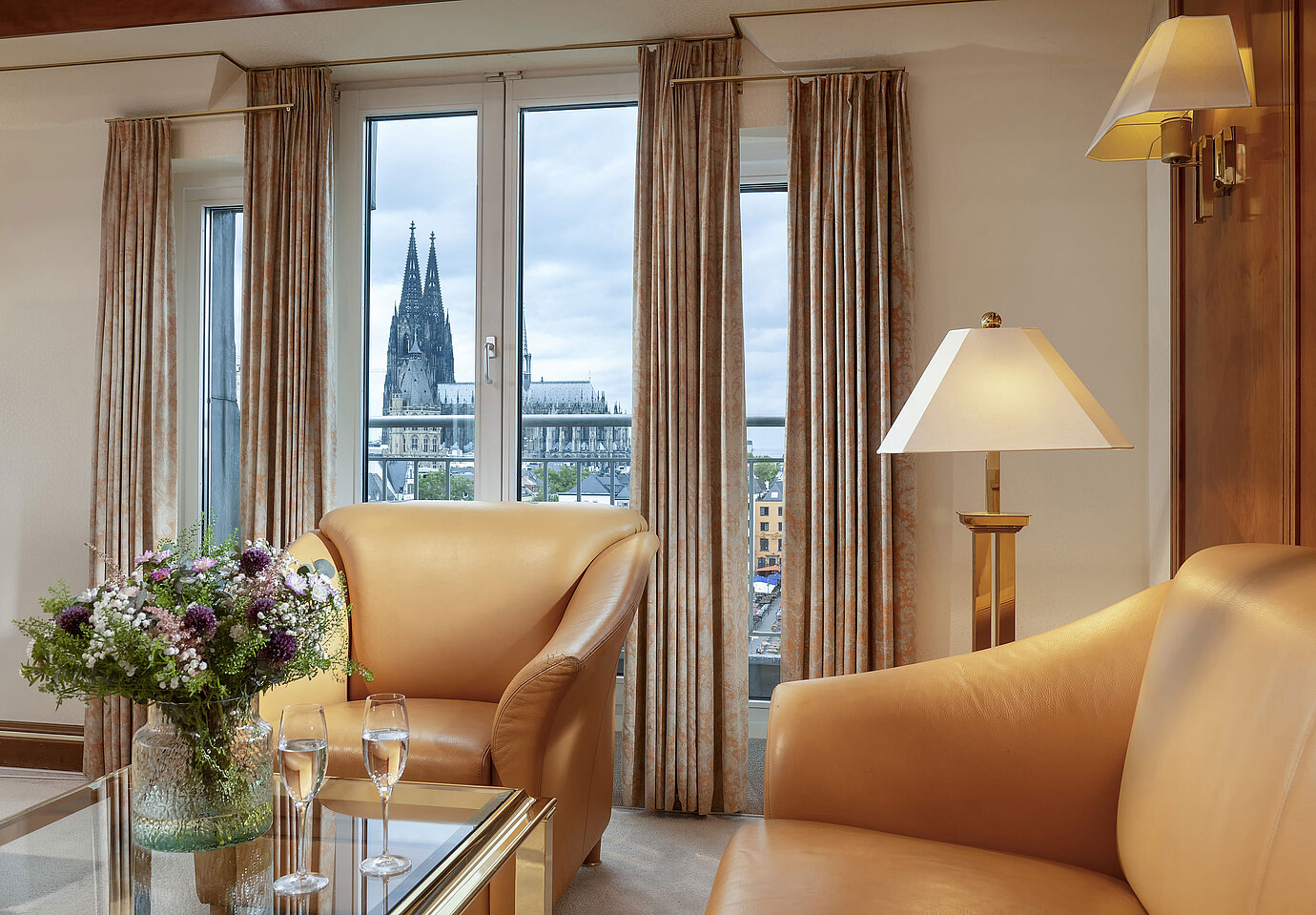  Elegant Heumarkt Suite at Maritim Hotel Cologne featuring comfortable leather chairs and a direct view of Cologne Cathedral.