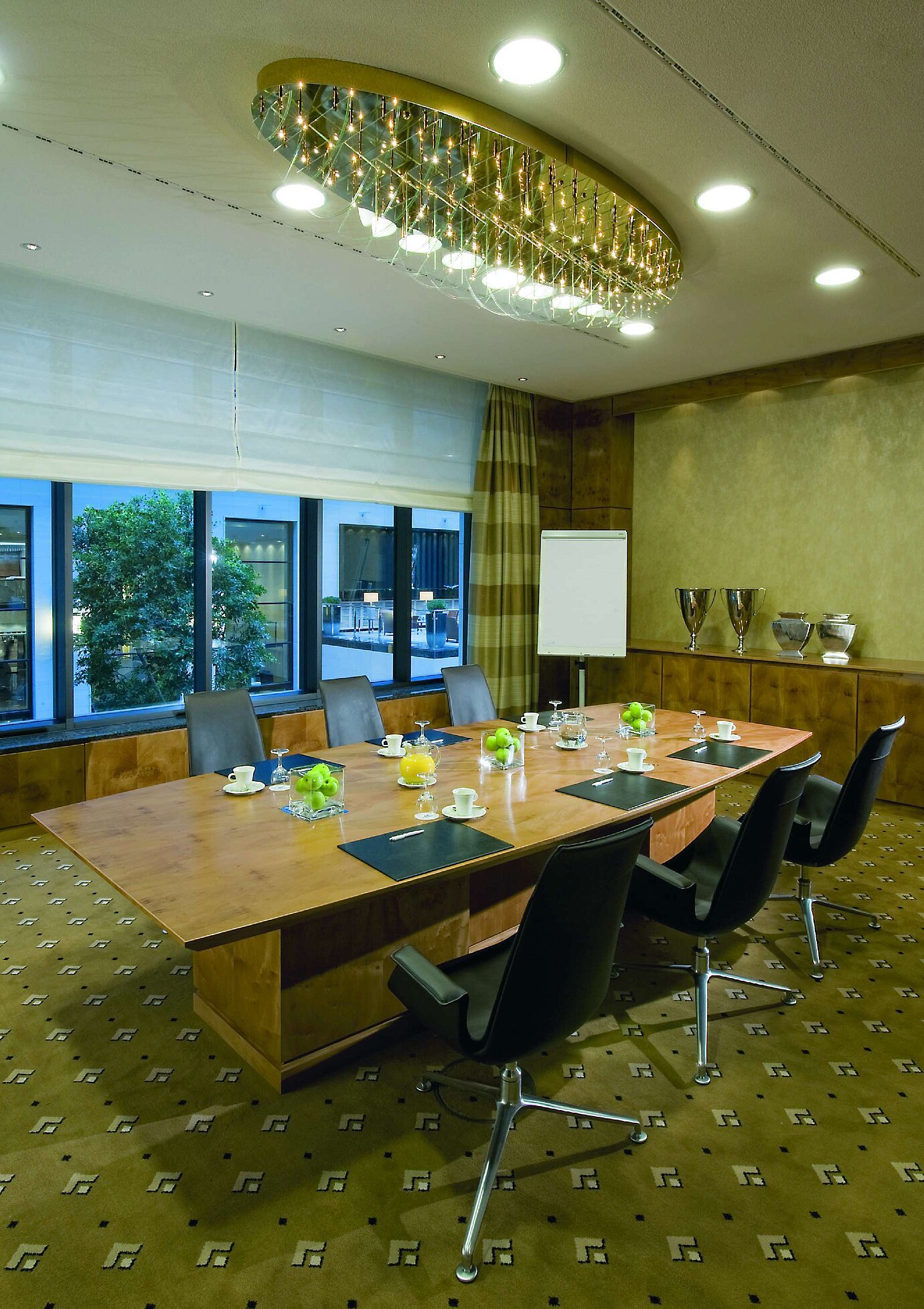 Sala de reuniones moderna en el Maritim Hotel Düsseldorf con mesa de madera elegante,sillas cómodas e iluminación sofisticada