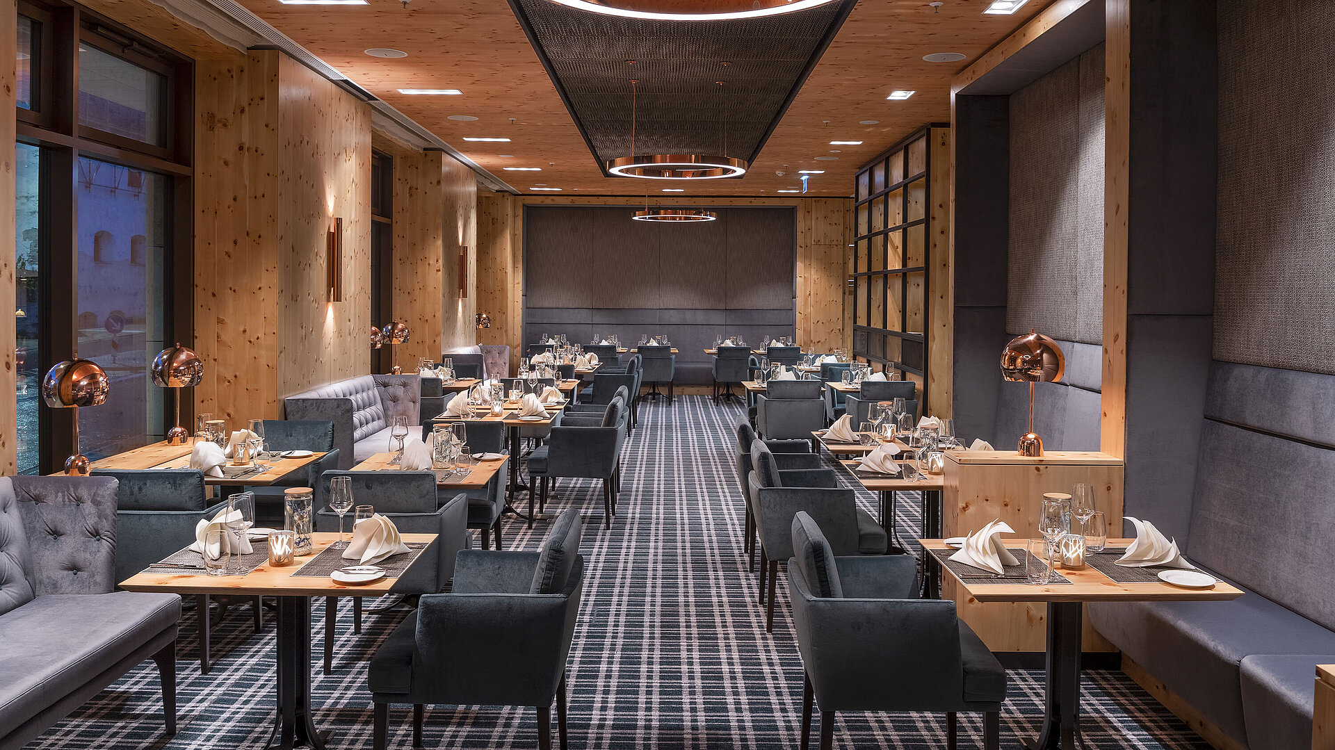Elegant restaurant with wooden design, cozy seating areas, and stylishly set tables at Maritim Hotel Ingolstadt.