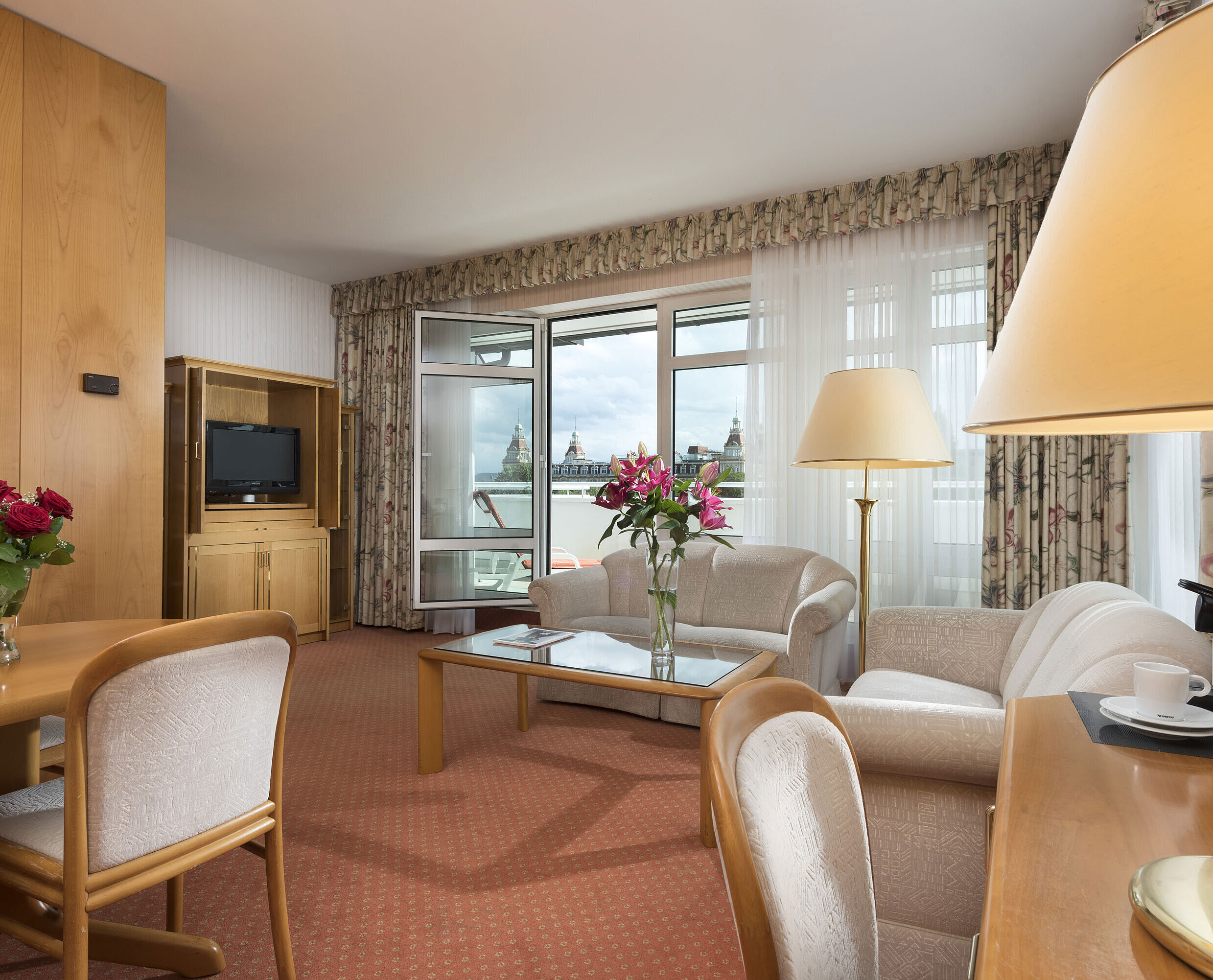 Spacious living area with flowers, sofa, dining table and view at Maritim Hotel Bad Wildungen