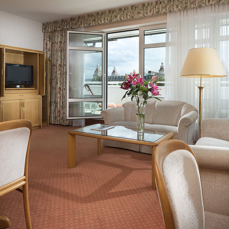 Salon spacieux avec fleurs, canapé, table et vue au Maritim Hotel Bad Wildungen