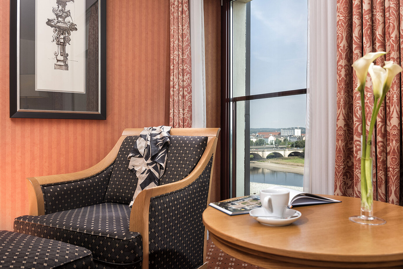 Cozy armchair detail with a view of the Elbe River and bridge, decorated with a scarf on the backrestCozy armchair detail at Maritim Hotel Dresden with a view of the Elbe River and bridge, decorated with a scarf on the backrestCozy armchair detail at Maritim Hotel Dresden with a view of the Elbe River and bridge, decorated with a scarf on the backrestCozy armchair detail at Maritim Hotel Dresden with a view of the Elbe River and bridge, decorated with a scarf on the backrest.