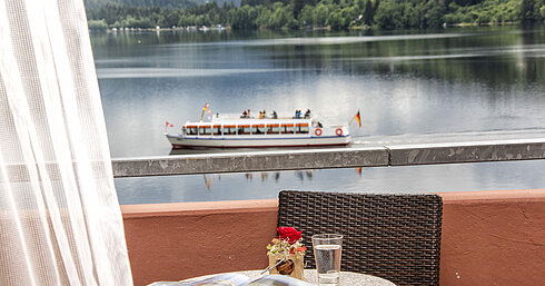 Balcón con vista al lago Titisee y barco en movimiento desde el Maritim Hotel