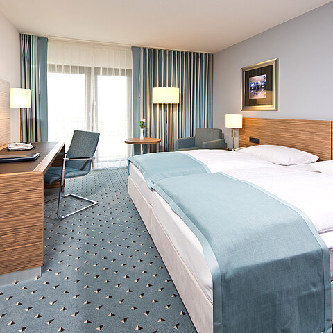 Comfort room at Maritim Hotel Darmstadt with modern design, desk, cozy seating area, and large windows.