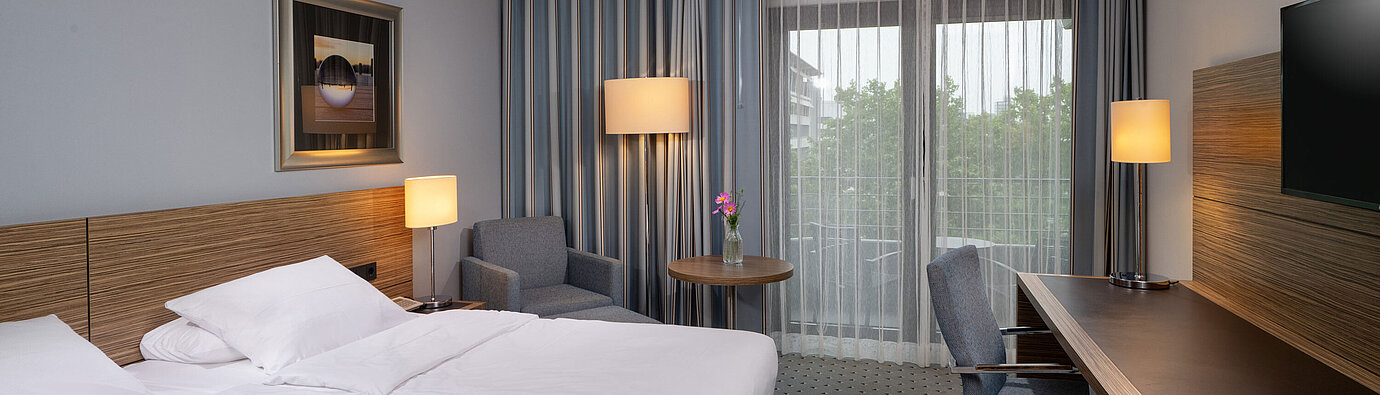 Vista completa della camera Comfort al Maritim Hotel Darmstadt con letto, scrivania e accesso al balcone