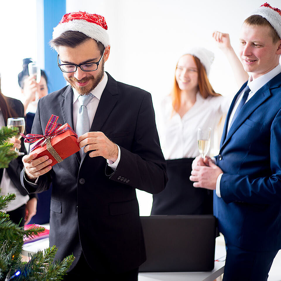 © Nichizhenova Elena - AdobeStock.com Colleagues exchanging gifts at a hotel Christmas party