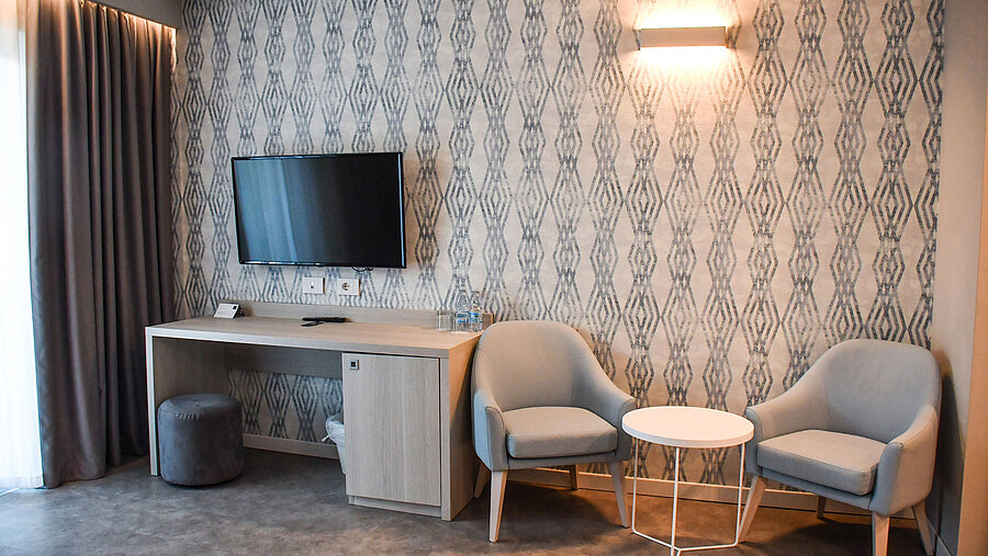 Modern seating area with TV and desk in the room at Maritim Resort Calabria