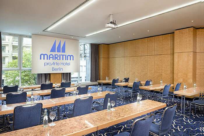 Salle de conférence au Maritim proArte Hotel Berlin avec sièges en rangée et écran de projection.