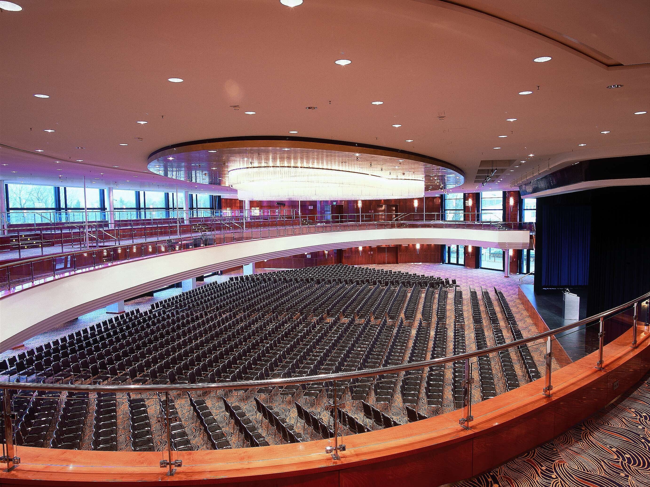 Elegante sala de conferencias en el Maritim Hotel Düsseldorf con cientos de asientos, arquitectura moderna y gran escenario.
