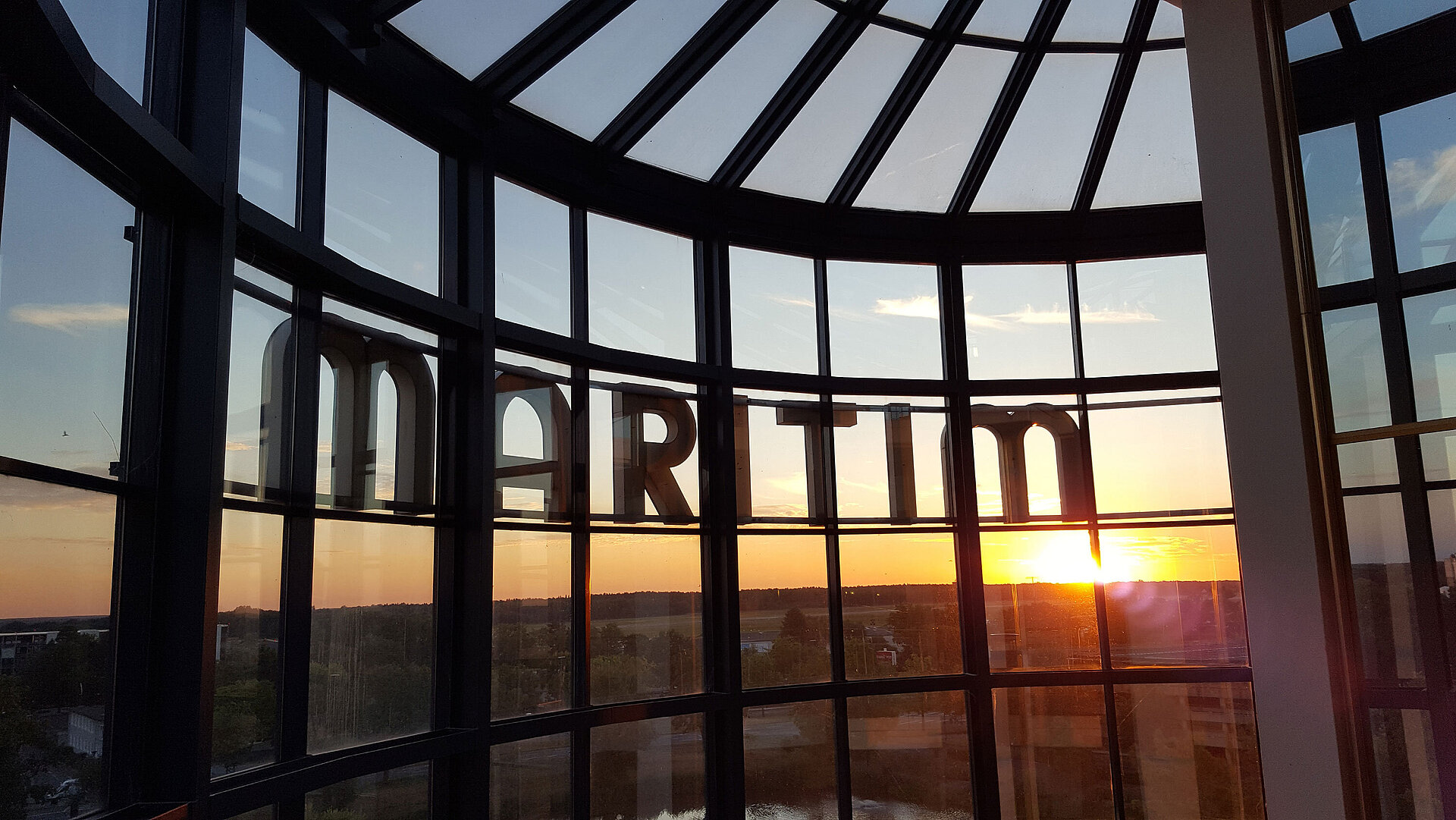 Vue spectaculaire du coucher de soleil à travers la façade vitrée de l’hôtel.