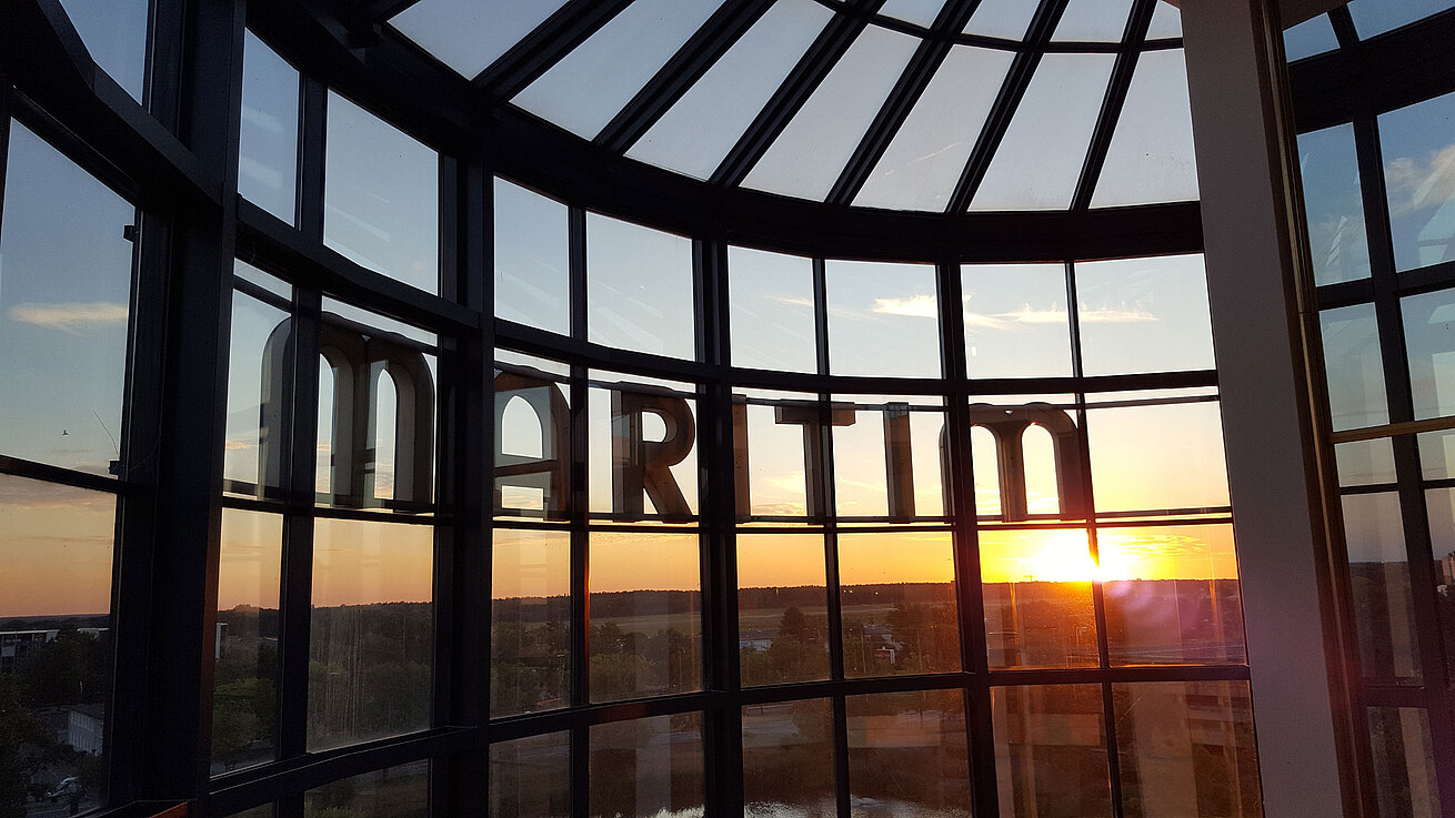 Vue spectaculaire du coucher de soleil à travers la façade vitrée de l’hôtel.