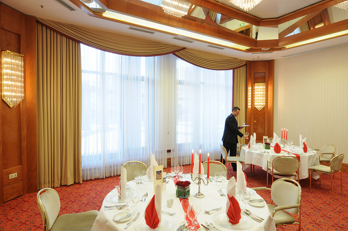 Salle de banquet élégamment dressée avec bougies et serviettes rouges au Maritim Hotel Magdeburg.