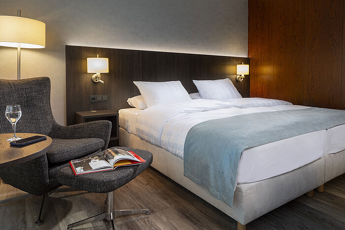Elegant Superior double room at Maritim Hotel Bremen with cozy armchair, reading material, and relaxing ambiance.