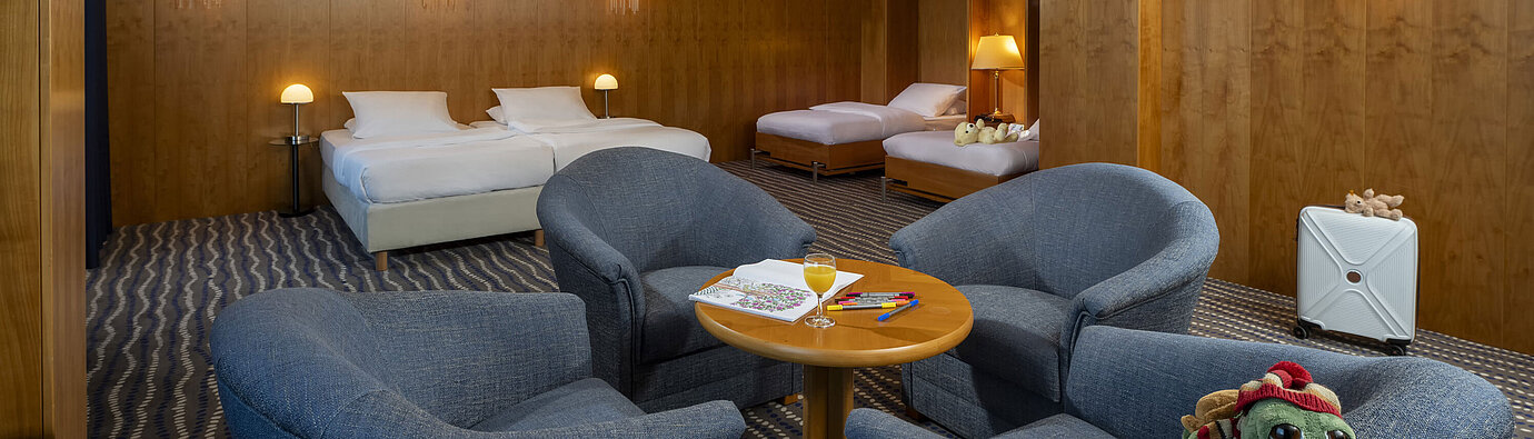 Chambre familiale supérieure spacieuse au Maritim Hotel Magdeburg avec deux lits doubles, coin salon et détails adaptés aux enfants.