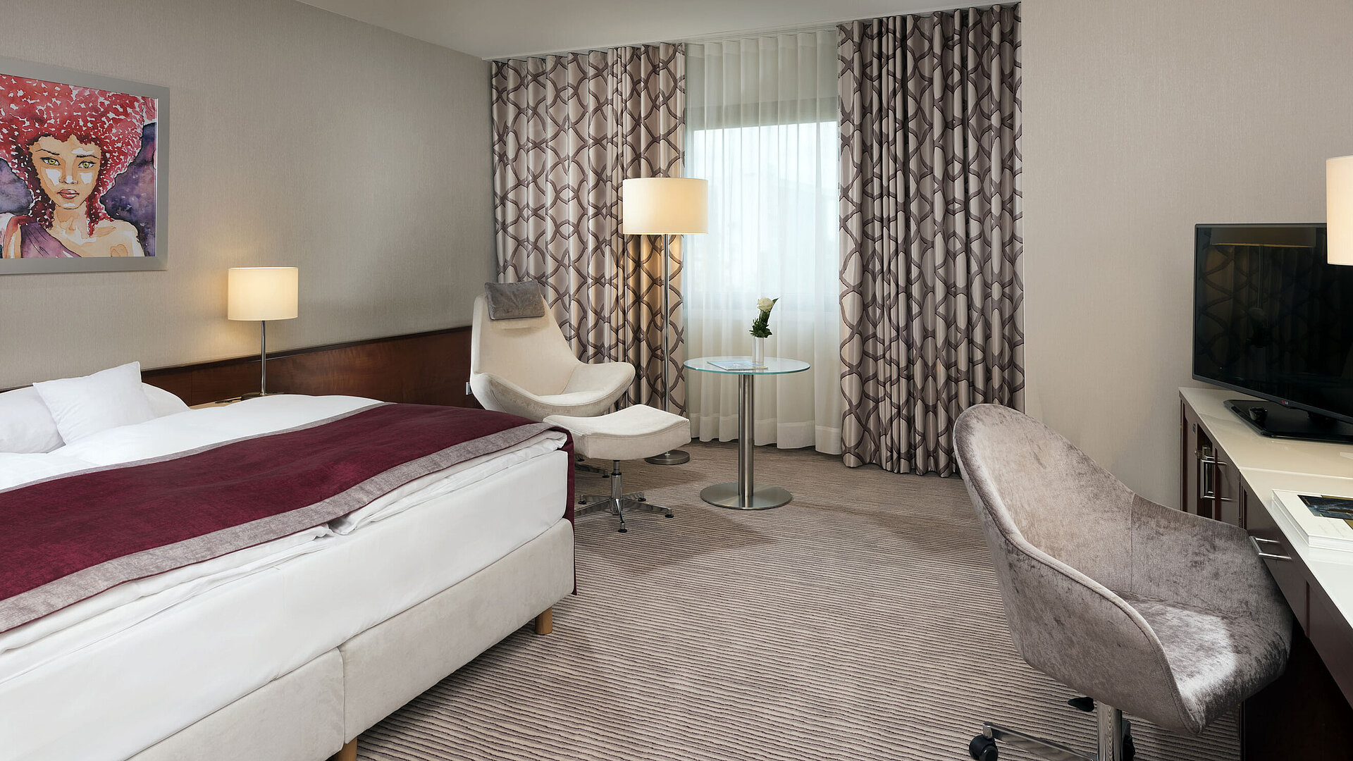 Habitación Comfort en el Hotel Maritim Bonn con cama acogedora, sillas, escritorio y cortinas modernas.