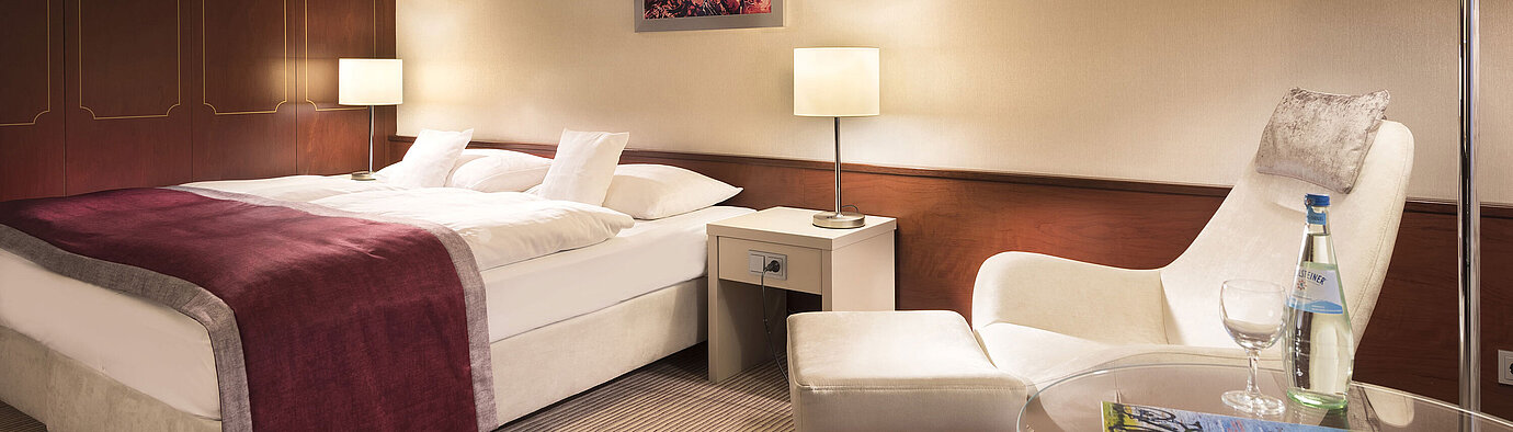 Habitación clásica en el Maritim Hotel Bonn, amueblada cómodamente con cama doble, sillón, mesa e iluminación moderna.