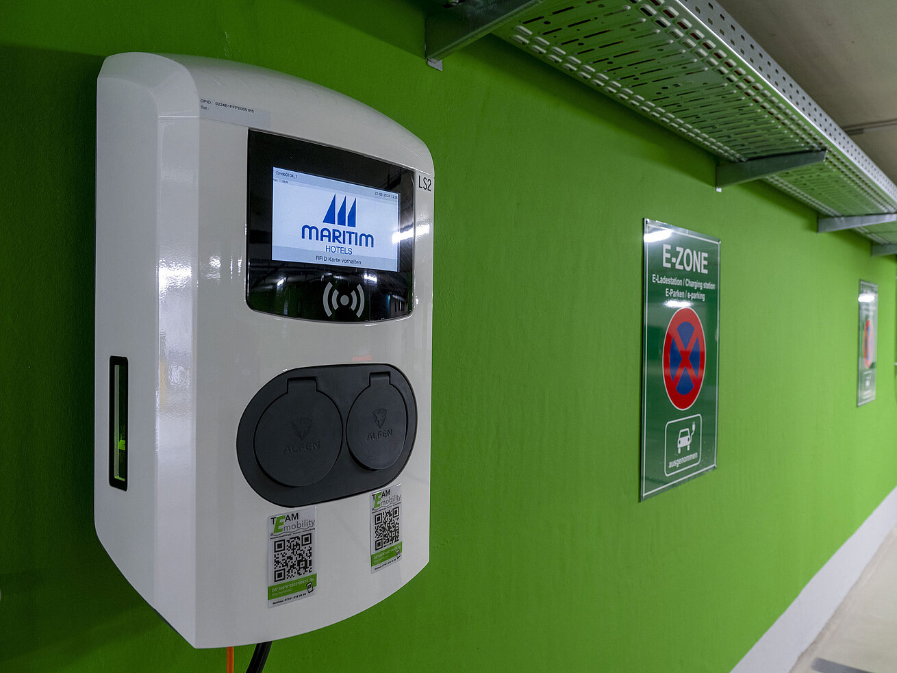 Close-up of an electric vehicle charging station with the Maritim Hotels logo in the E-Zone of the parking garage.