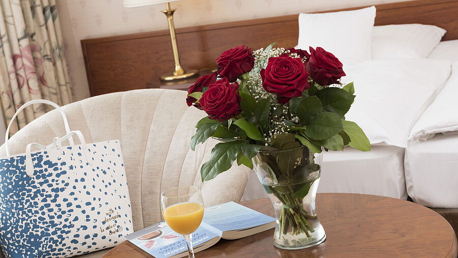 Fresh roses, juice and reading material on table in double room of Maritim Hotel Bad Wildungen