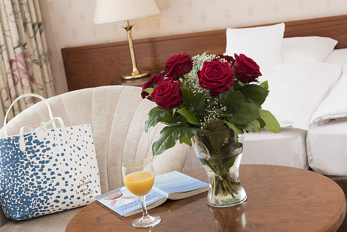 Fresh roses, juice and reading material on table in double room of Maritim Hotel Bad Wildungen