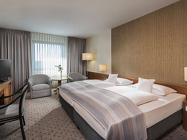 Modern classic double room with a cozy double bed, seating area, and desk at Maritim Hotel Hannover.
