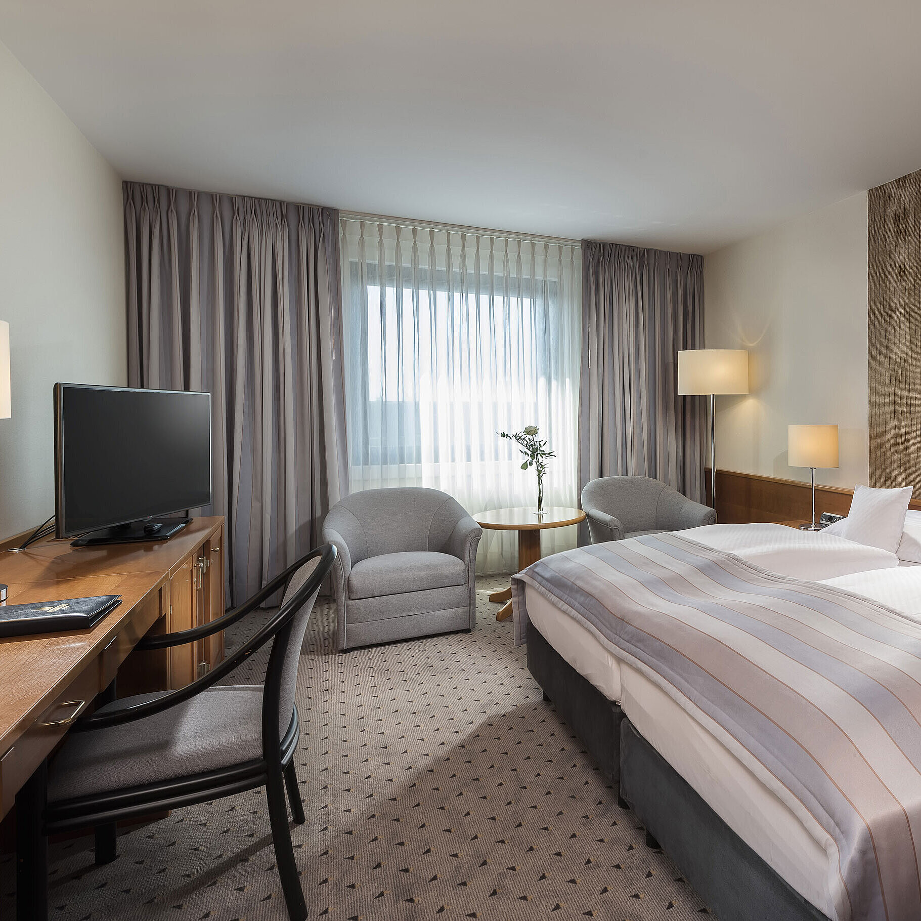 Modern classic double room with a cozy double bed, seating area, and desk at Maritim Hotel Hannover.