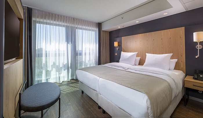 Habitación doble espaciosa con diseño moderno, camas cómodas y vista a la ciudad en Maritim Hotel Ingolstadt.