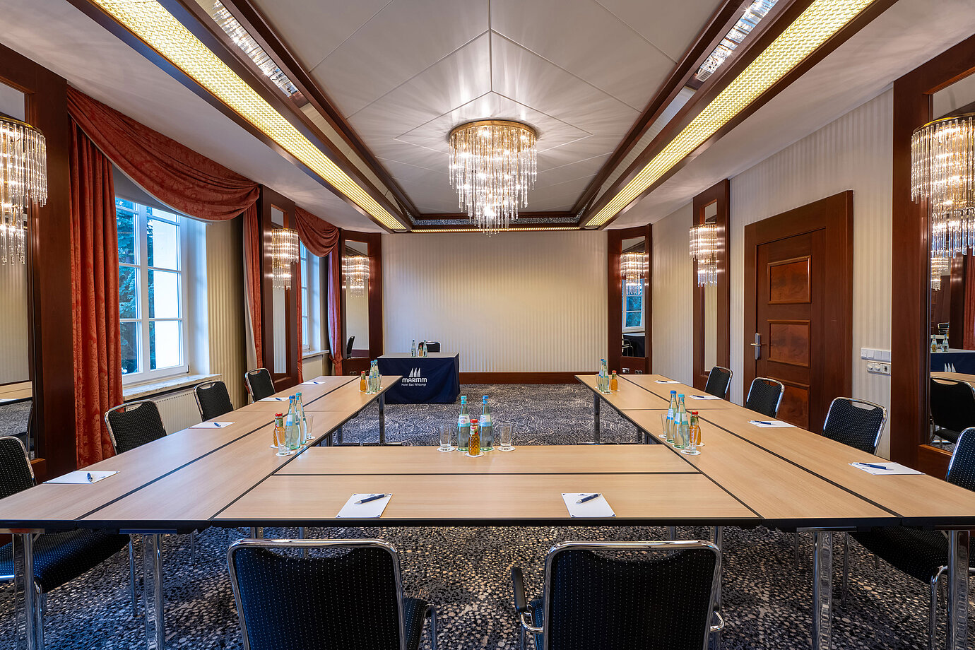 Elegant meeting room at a Maritim hotel with U-shaped table setup and presentation screen.