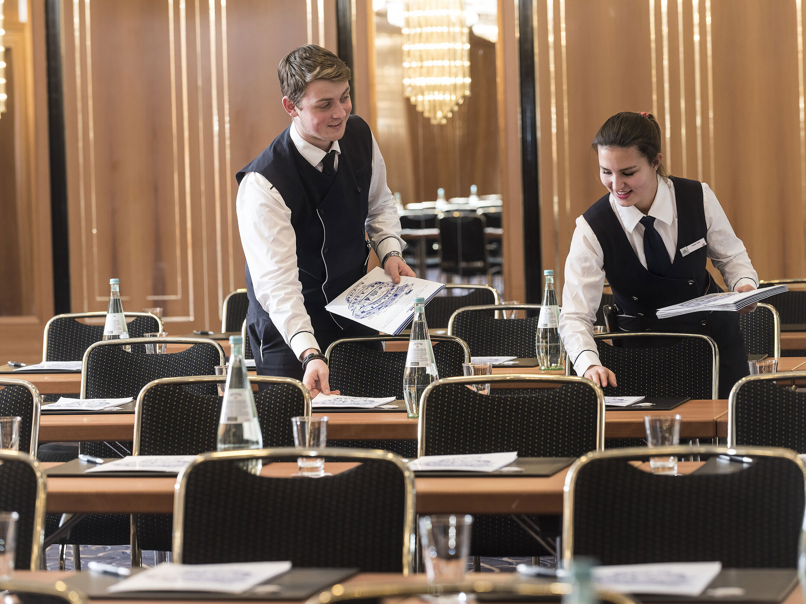 Two staff members place conference documents on tables at Maritim Hotel Stuttgart