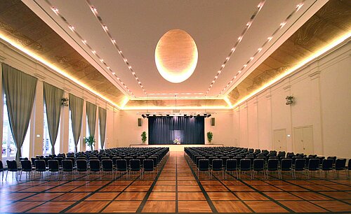 Elegant banquet hall at Maritim Hotel Fulda with a stage, stylish lighting, and seating for events.