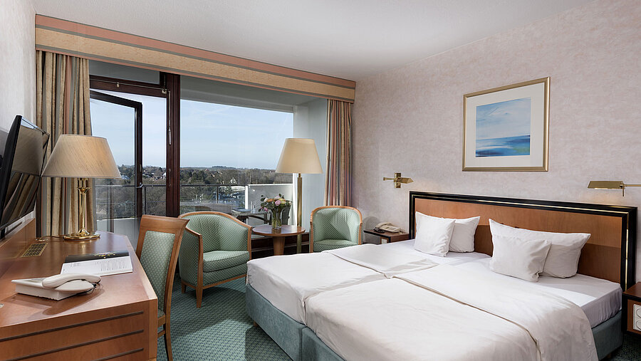 Comfort room at Maritim Seehotel Timmendorfer Strand with twin beds, seating area, desk, and balcony view.