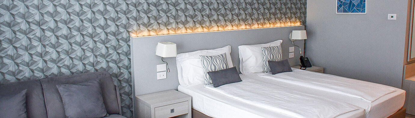 Spacious room at Maritim Resort Calabria with twin bed, sofa and stylish wall design