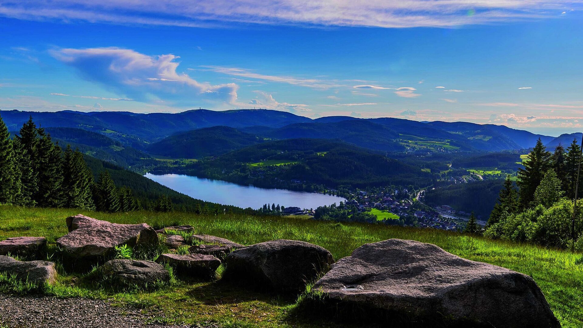 Vista amplia del Titisee y la Selva Negra desde el Hochfirst con prados, rocas y colinas arboladas