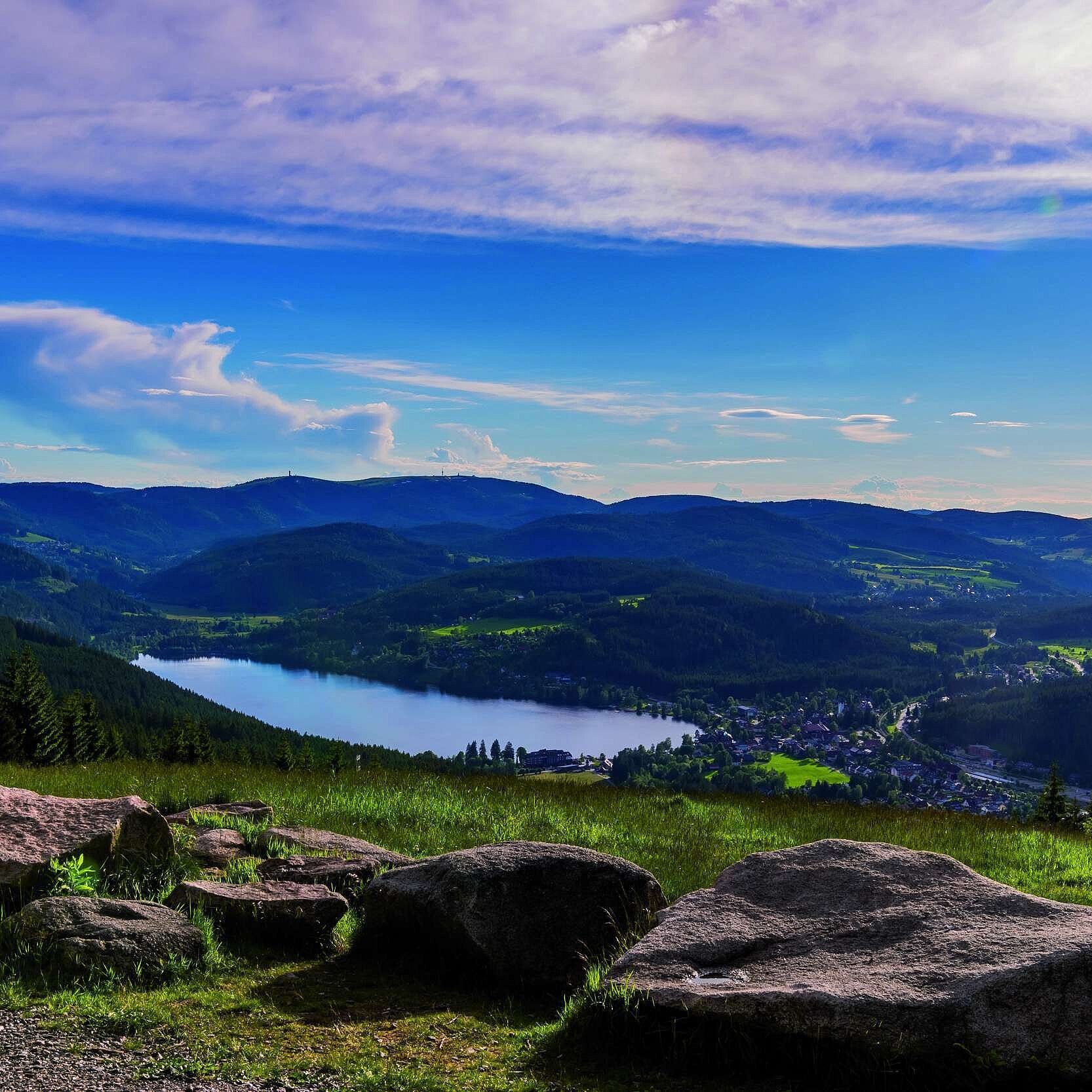 Vista amplia del Titisee y la Selva Negra desde el Hochfirst con prados, rocas y colinas arboladas