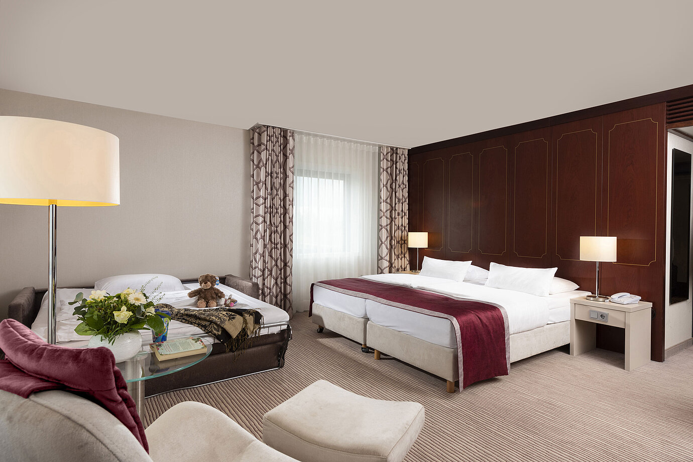 Habitación familiar Comfort en el Hotel Maritim Bonn con cama doble, sofá cama, sillón y arreglo floral.