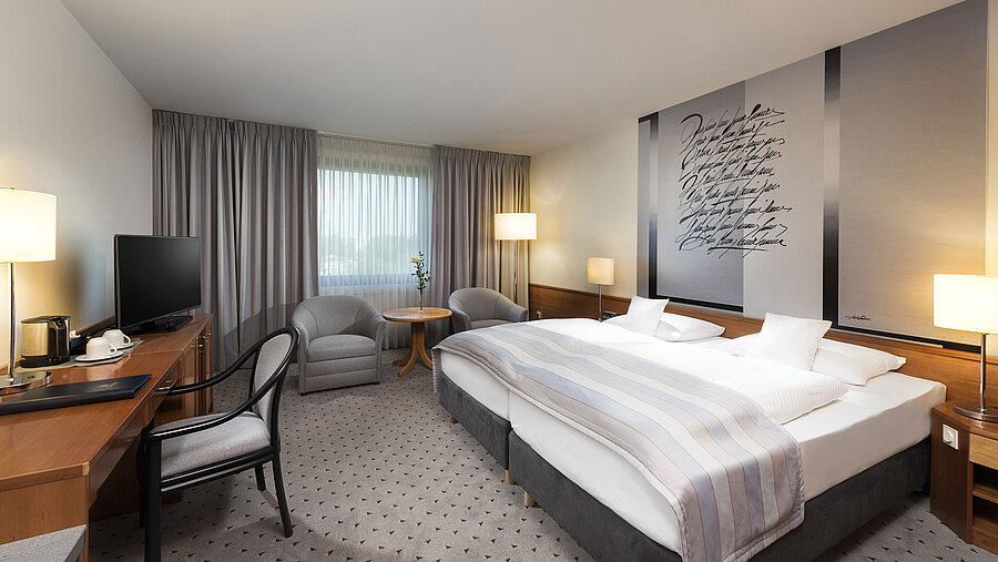 Habitación doble Classic moderna con cama doble acogedora, zona de estar y escritorio en el hotel Maritim Hannover.