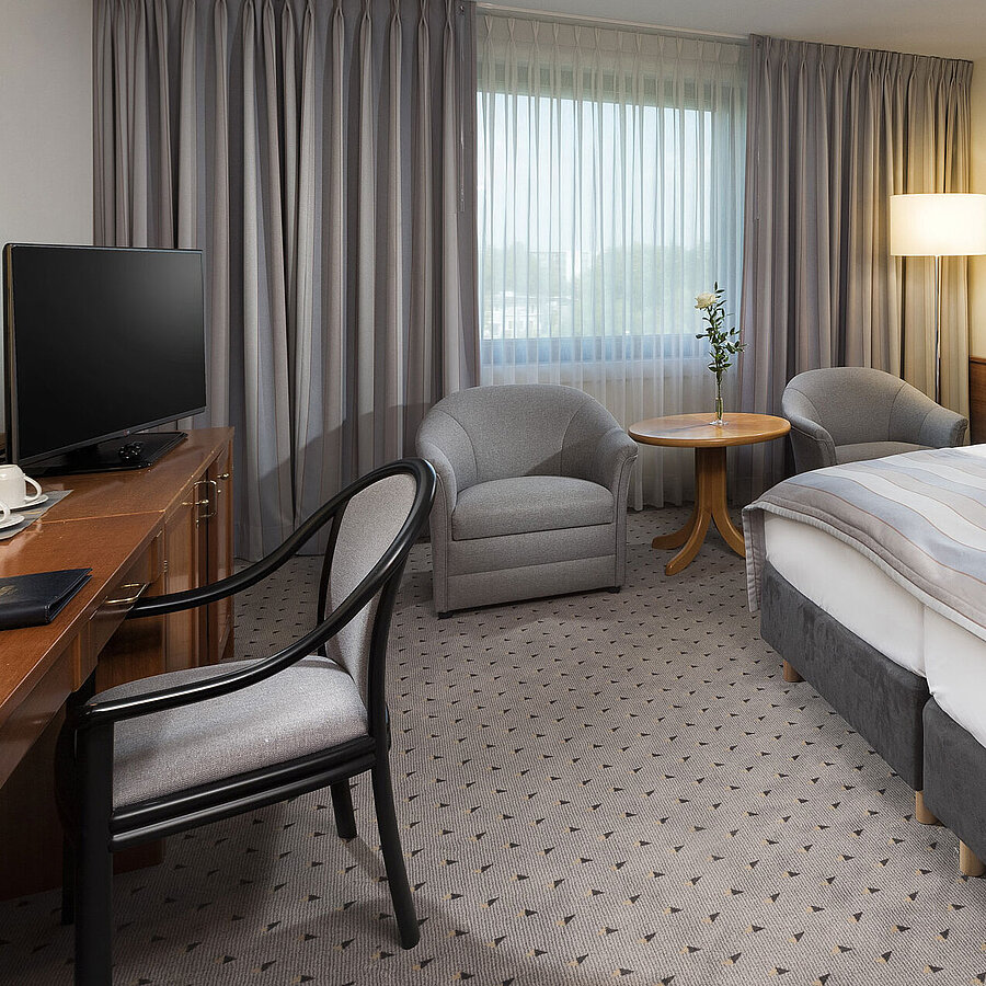 Chambre double Classic moderne avec un lit double confortable, coin salon et bureau à l’hôtel Maritim Hannover.