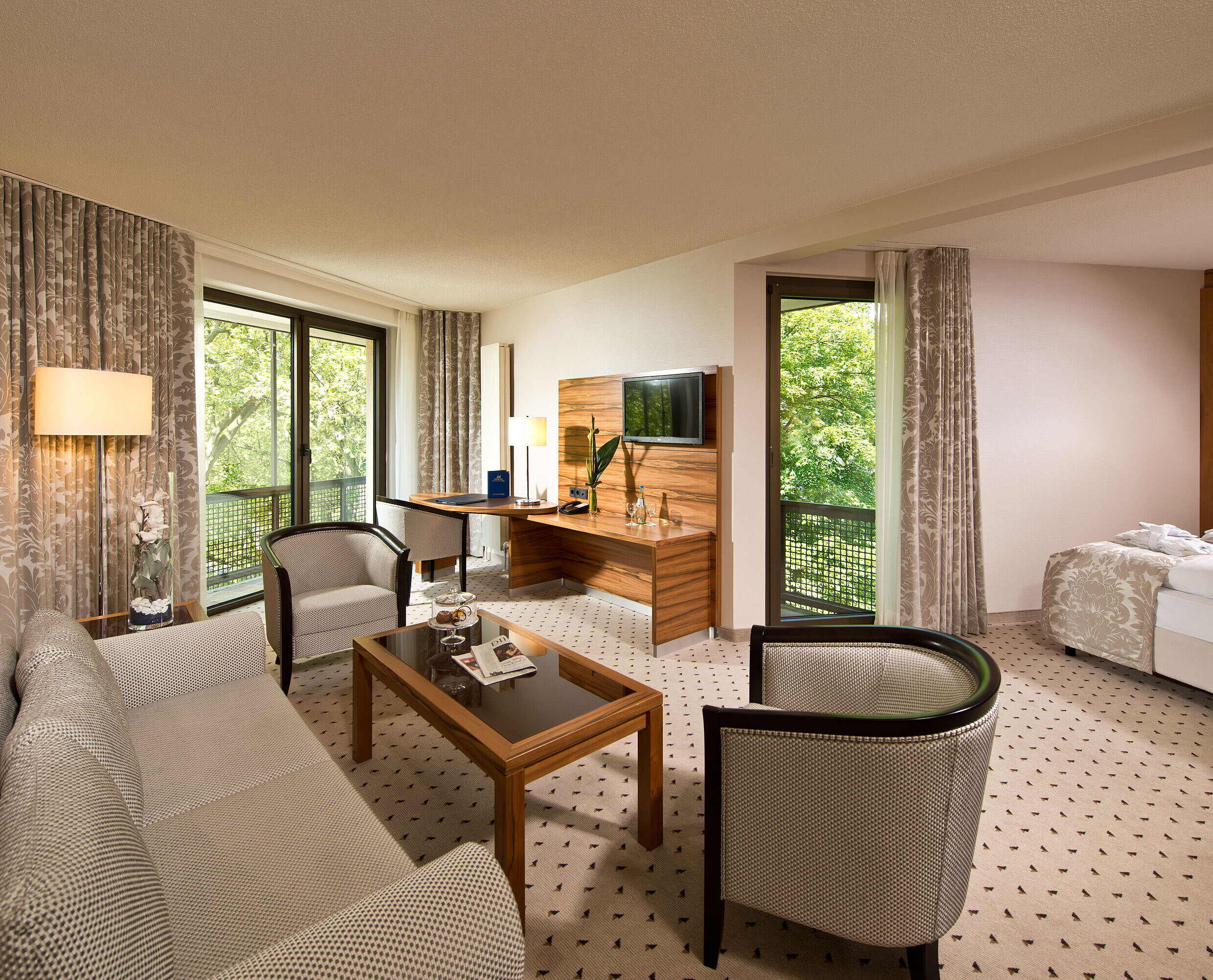 Suite spacieuse à l'hôtel Maritim Bad Homburg avec salon séparé, balcon et vue sur la verdure.