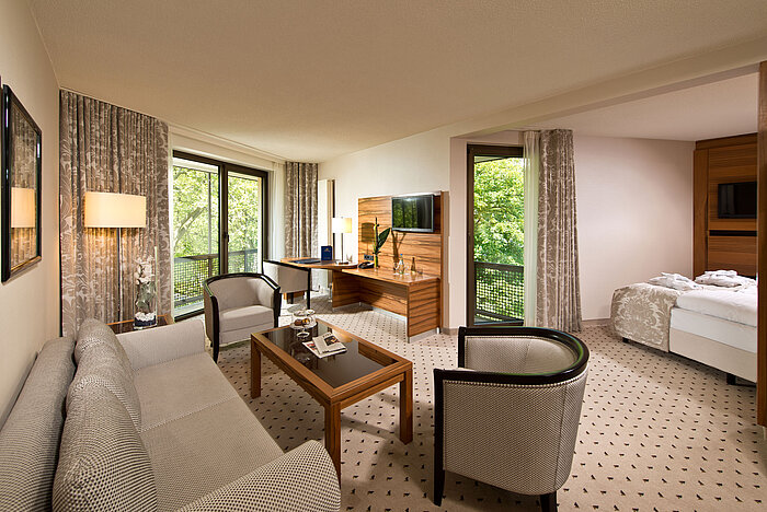 Suite spacieuse à l'hôtel Maritim Bad Homburg avec salon séparé, balcon et vue sur la verdure.