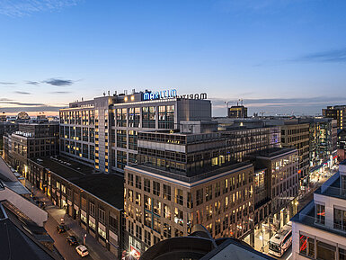 Vista del Maritim proArte Hotel Berlín al anochecer, rodeado de edificios modernos en el corazón de Berlín.