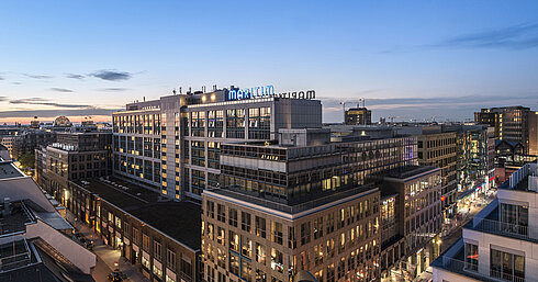 Vista del Maritim proArte Hotel Berlino al crepuscolo, circondato da edifici moderni nel cuore di Berlino.
