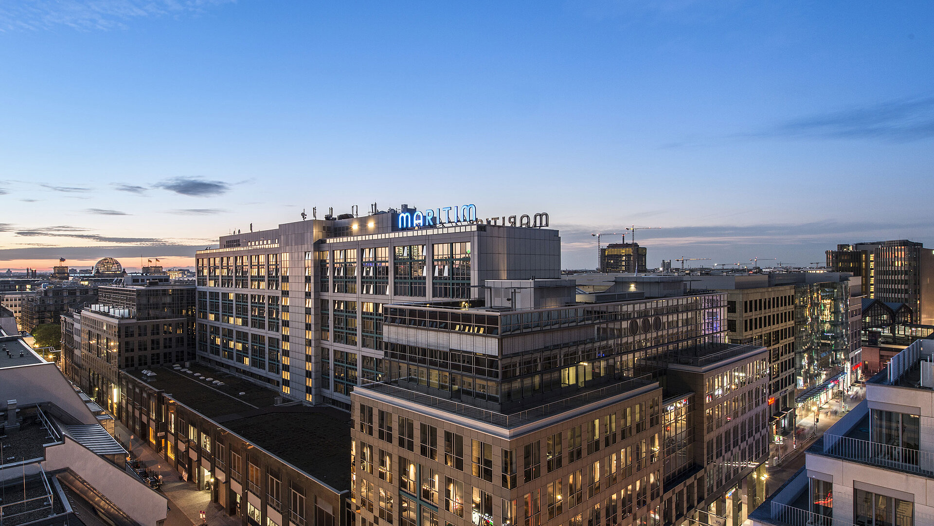 Vista del Maritim proArte Hotel Berlino al crepuscolo, circondato da edifici moderni nel cuore di Berlino.
