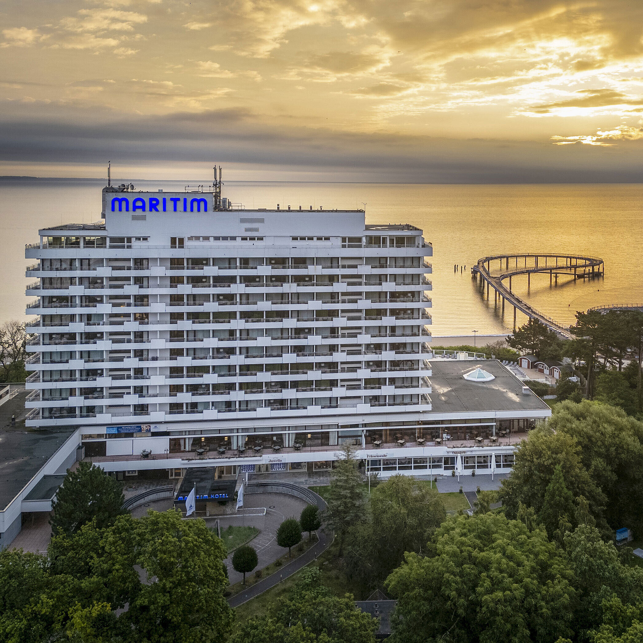 Vue extérieure Maritim Seehotel Timmendorfer Strand au lever du soleil avec une jetée et vue sur la mer.