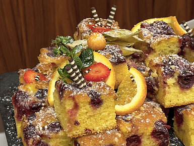 Coffee break Fruity cake with cherries and orange slices, decorated with mint and chocolate rolls, served at Maritim Hotel Darmstadt.