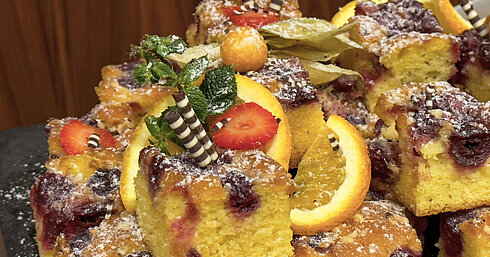 Fruity cake with cherries and orange slices, decorated with mint and chocolate rolls, served at Maritim Hotel Darmstadt.