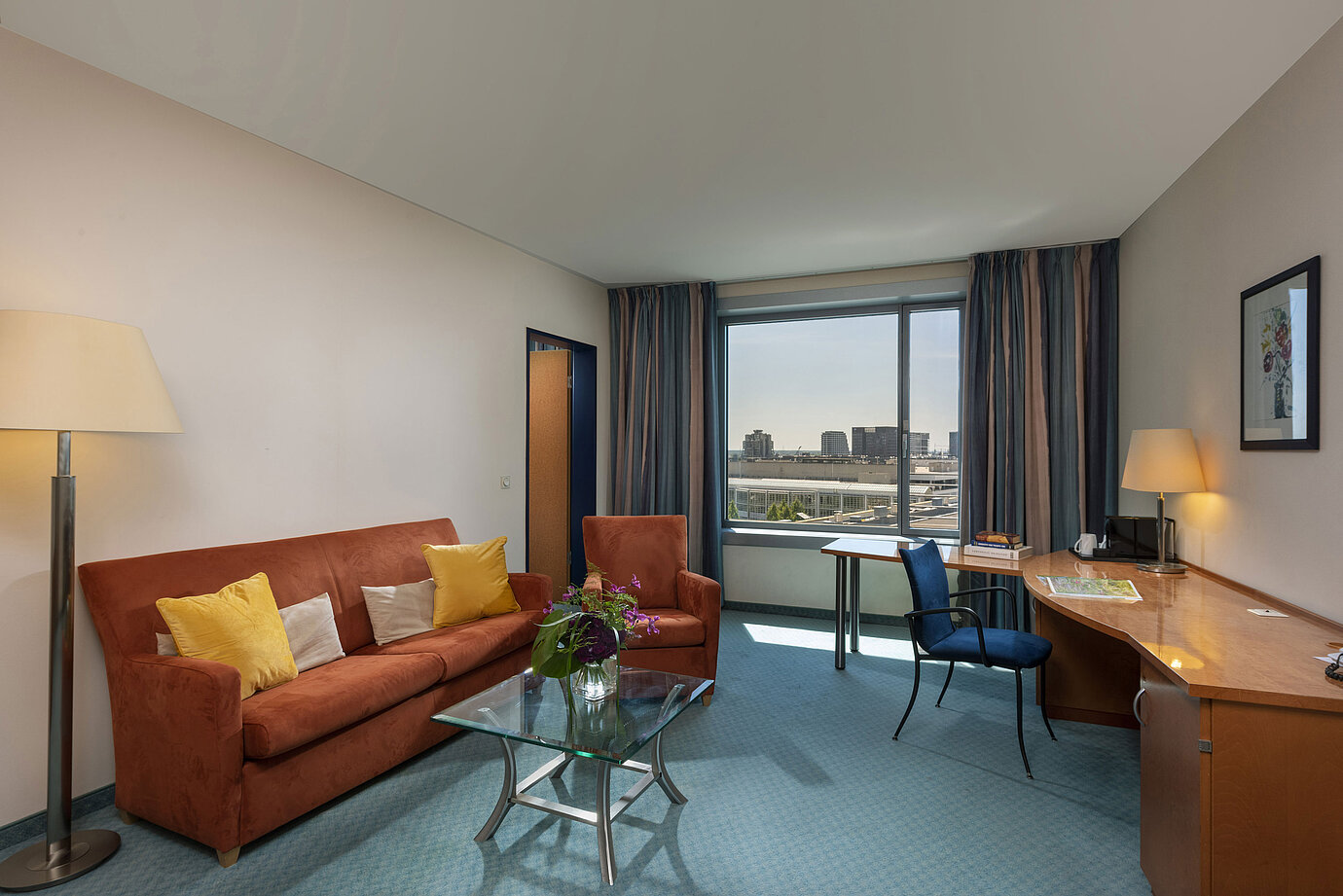 Junior Suite du Maritim Hotel Frankfurt avec salon séparé, canapé, bureau et vue panoramique sur la ville.