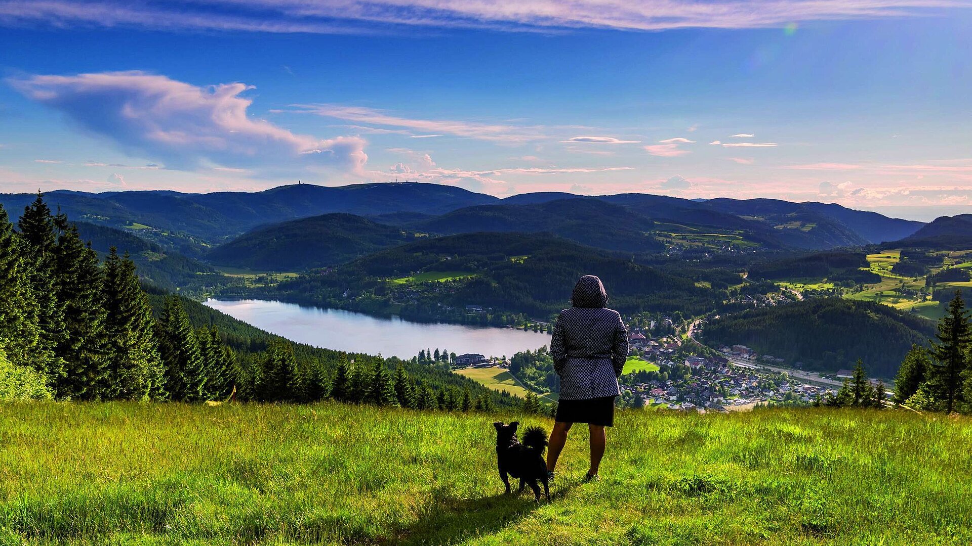 Femme avec chien admirant la vue sur le lac Titisee et la Forêt-Noire depuis le Hochfirst