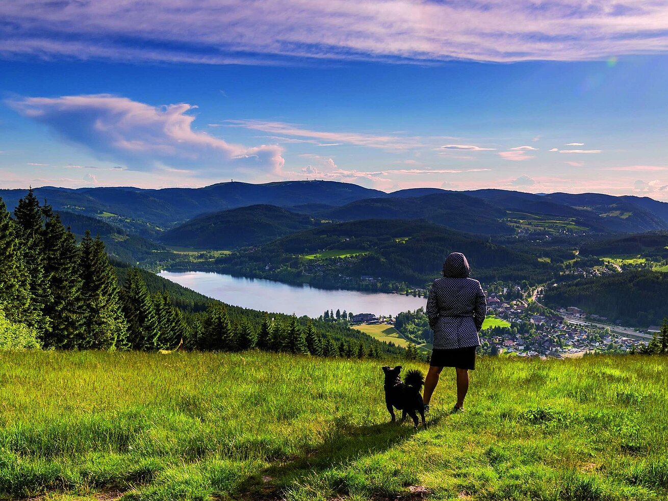 Mujer con perro disfrutando de la vista al Titisee y la Selva Negra desde el Hochfirst
